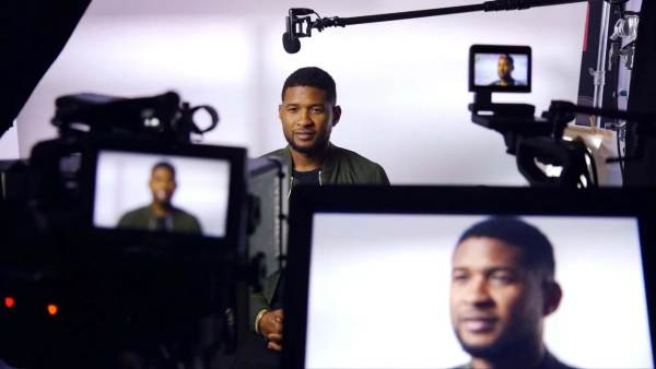 Usher sitting on a film set in front of multiple cameras with his face displayed on all monitors.